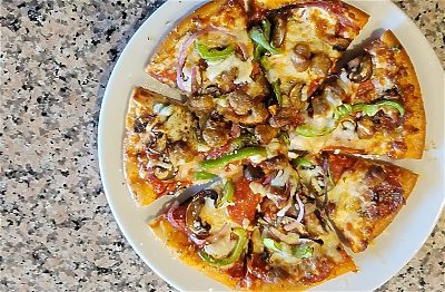 Meat and vegetable pizza on a round plate