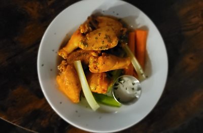 Layered sandwich with meat, coleslaw, and pickles on a plate